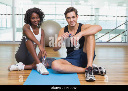 Personal trainer and client smiling at camera on exercise mat Stock Photo