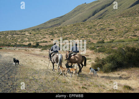 Two Gauchos on horseback with dogs Patagonia Argentina Stock Photo