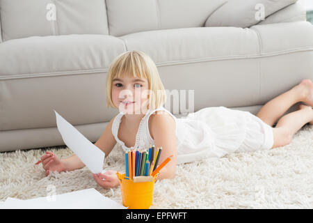Smiling litlle girl drawing lying on the floor Stock Photo