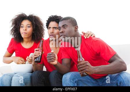 Nervous football fans in red on the sofa Stock Photo