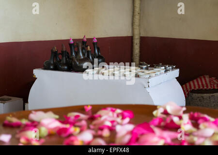 Selective focus on table with traditional coffee pots and cups with defocused flower petals in the foreground. Indoor setting. Stock Photo