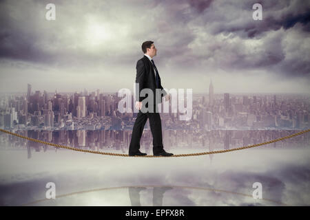 Composite image of handsome businessman stepping on tightrope Stock Photo