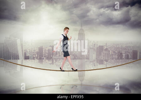 Composite image of businesswoman doing a balancing act on tightrope Stock Photo
