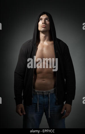strong man wearing black hoodie isolated on dark