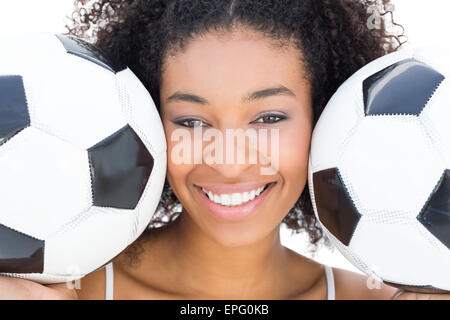 Pretty girl with afro hairstyle smiling at camera holding footballs Stock Photo