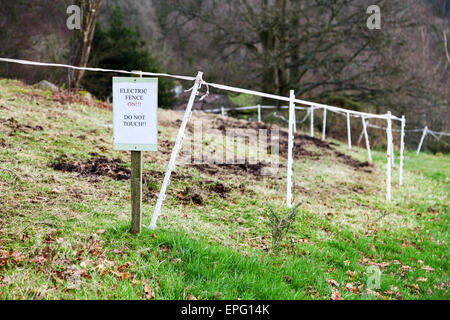 A sign in a field saying electric fence on do not touch Stock Photo