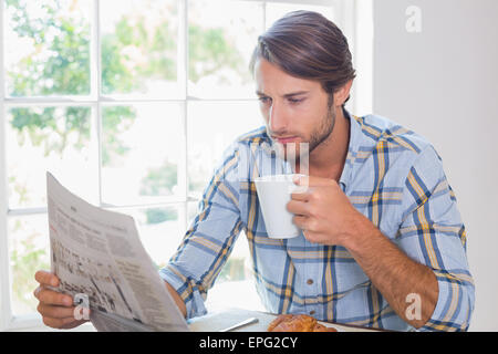 Casual man having coffee while reading newspaper Stock Photo