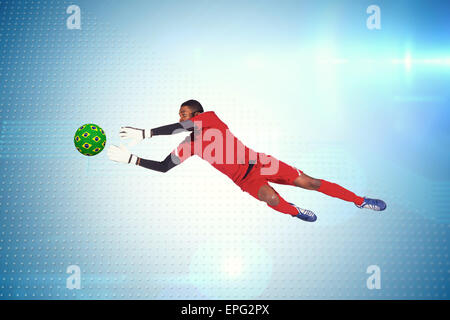 Composite image of goalkeeper in red making a save Stock Photo