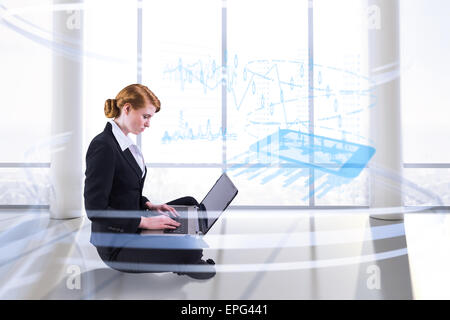 Composite image of redhead businesswoman using her laptop Stock Photo