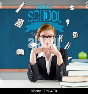 Composite image of redhead teacher sitting at desk Stock Photo
