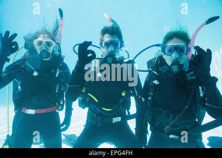 Friends on scuba training submerged in swimming pool looking to camera Stock Photo