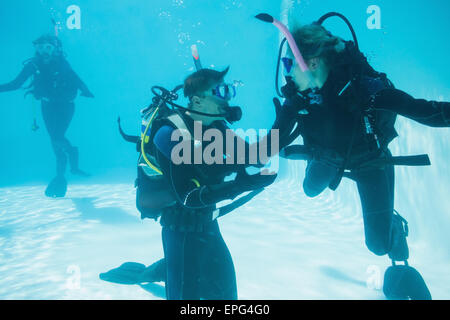 Friends on scuba training submerged in swimming pool Stock Photo