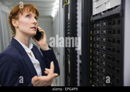 Pretty technician talking on phone while looking at server Stock Photo