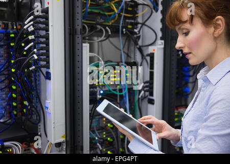 Technician using tablet pc while analysing server Stock Photo