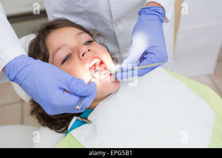 Pediatric dentist examining a little boys teeth in the dentists chair Stock Photo