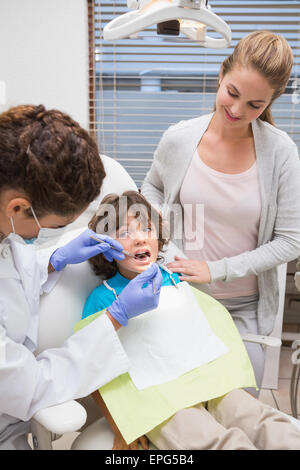 Pediatric dentist examining a little boys teeth with his mother Stock Photo