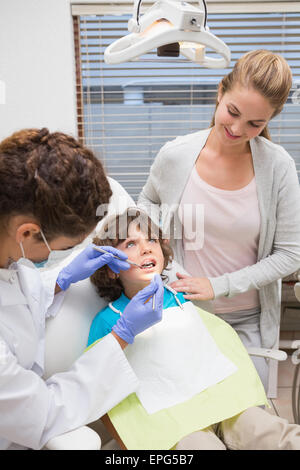 Pediatric dentist examining a little boys teeth with his mother Stock Photo