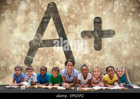 Composite image of cute pupils smiling at camera with teacher Stock Photo