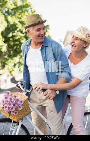 Happy mature couple going for a bike ride in the city Stock Photo