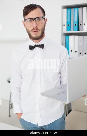 Nerdy businessman holding laptop looking at camera Stock Photo