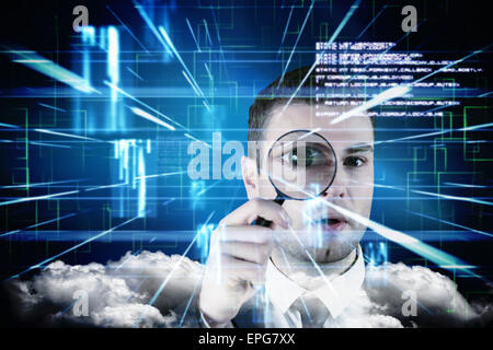 Composite image of businessman looking through magnifying glass Stock Photo