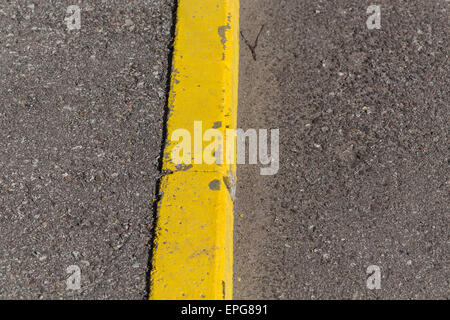 Yellow curb stone border and asphalt road Stock Photo