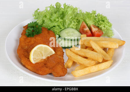 Wiener Schnitzel Gericht mit Pommes, Salat und Zitrone Stock Photo