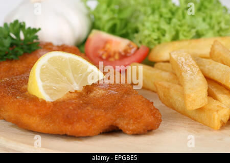 Paniertes Wiener Schnitzel Gericht mit Pommes, Zitrone und Salat Stock Photo