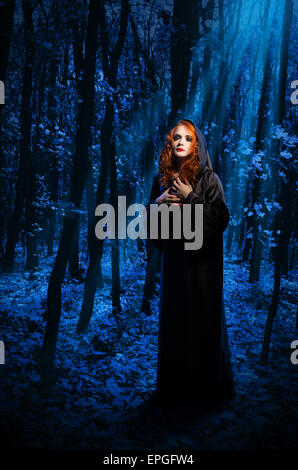 Young witch at night forest Stock Photo