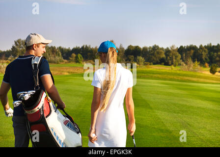 Sportive couple playing golf on a golf course walking to the next hole Stock Photo
