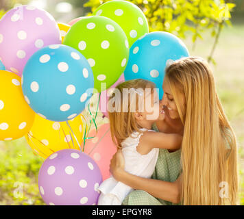 Happy woman and her little daughters with ballons outdoors Stock Photo