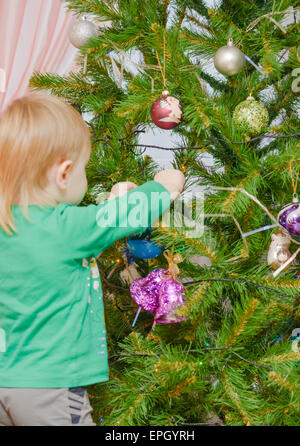 Blond boy decorates Christmas tree Stock Photo