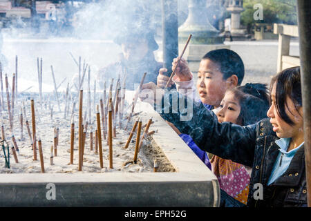 Chion-in temple in Kyoto. People standing around incense burner praying and waving the smoke from smouldering incense, osenko, sticks over themselves. Stock Photo