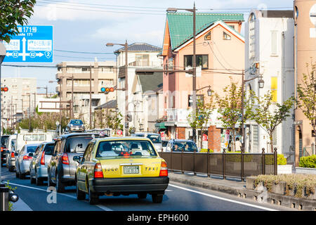 Traffic on route 171 in Nishinomiya, Japan, during the afternoon rush hour. Cars queuing at junction lights under large overhead blue direction sign Stock Photo