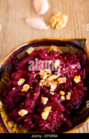 Grated beet (beetroot) with walnuts over rustic wooden table Stock Photo