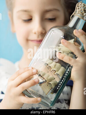Girl holding a toy ship in the bottle Stock Photo