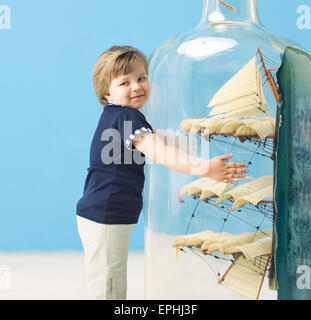 Little sailor holding a large bottle with a ship in Stock Photo