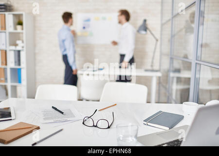Empty workplace in office with businessmen interacting on background Stock Photo