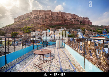 Rooftop cafe with view to Mehrangarh fort on the hill at cloudy sky in Jodhpur Blue city, Rajasthan, India Stock Photo