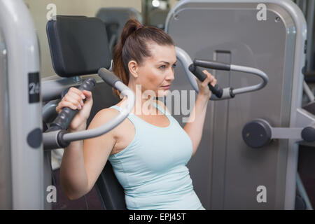 Fit brunette using weights machine for arms Stock Photo