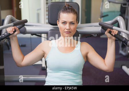 Fit brunette using weights machine for arms Stock Photo