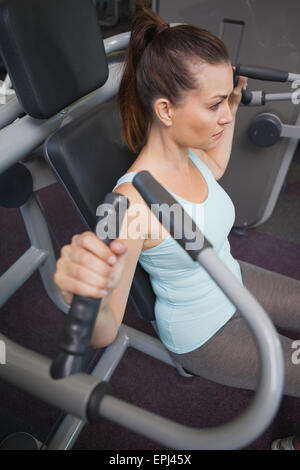 Fit brunette using weights machine for arms Stock Photo