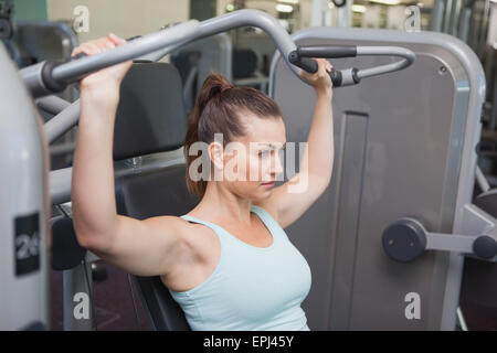 Fit brunette using weights machine for arms Stock Photo