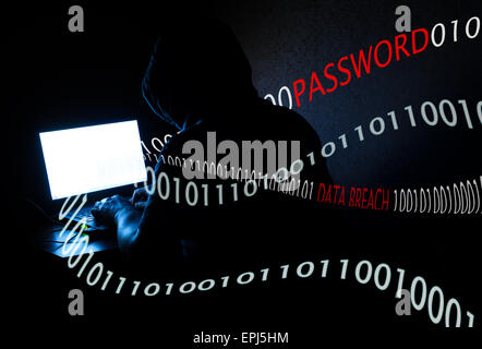 Singe male Computer hacker at work stealing confidential data and passwords from a notebook in a darkened room Stock Photo