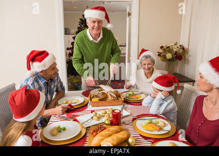 Grandfather in santa hat carving roast turkey at christmas Stock Photo