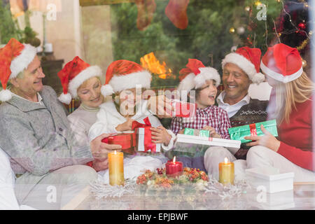 Multi generation family holding a lot of presents on sofa Stock Photo