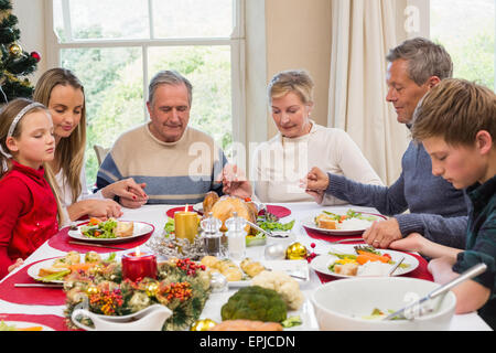 Extended family saying grace before christmas dinner Stock Photo