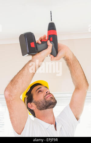 Construction worker drilling hole in ceiling Stock Photo