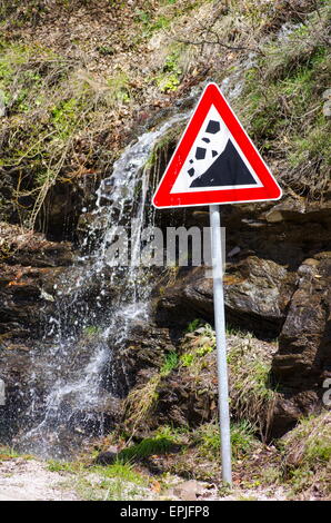 Small waterfall running behind a landslide sign outdoors Stock Photo