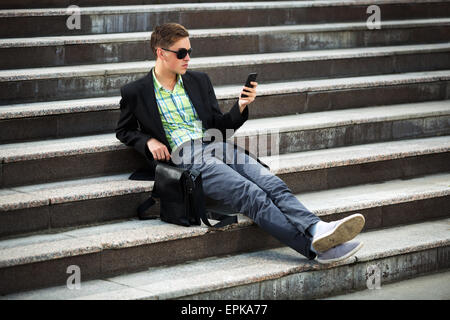 Young man with a mobile phone sitting on the steps Stock Photo